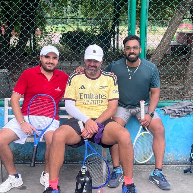 Three players courtside on the bench with their rackets
